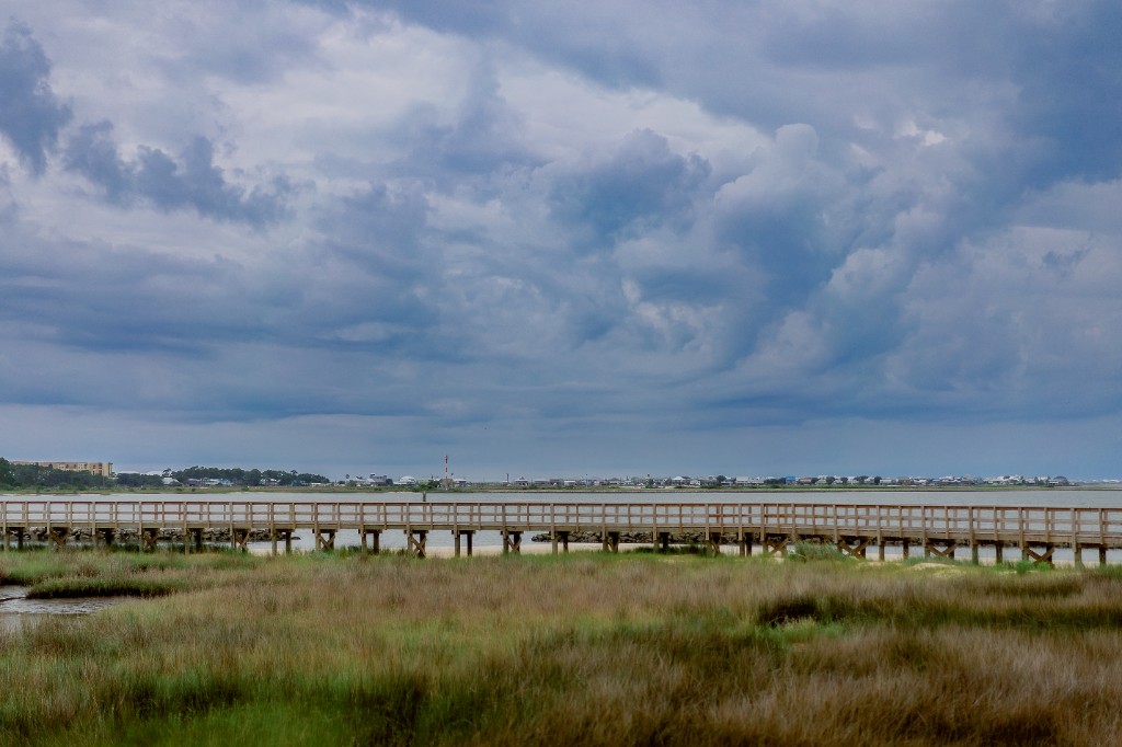 Boardwalk through coastal marsh under a stormy Gulf Coast sky