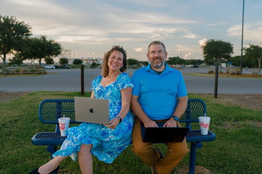 Anna and Bryan Cirlot sitting on a park bench with laptops